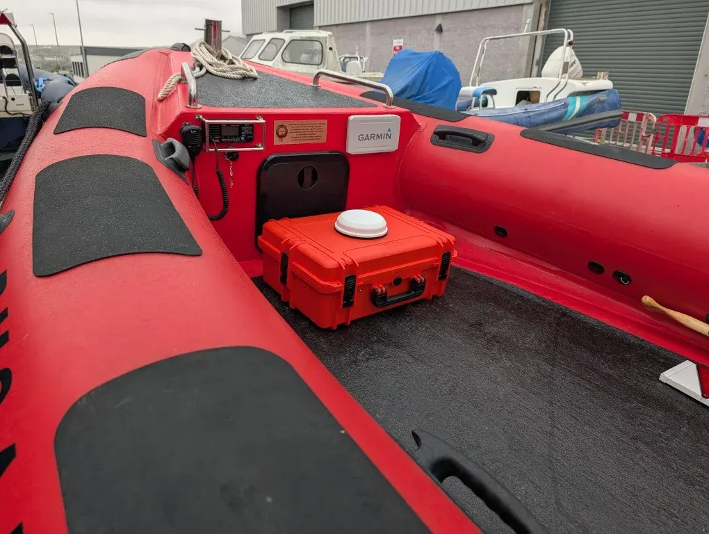 BRNKL Portable case secured in the bow of a red workboat RIB alongside the console and VHF radio