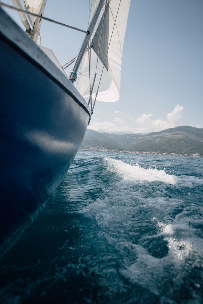 Sailing yacht heeling under full sail with a coastline astern