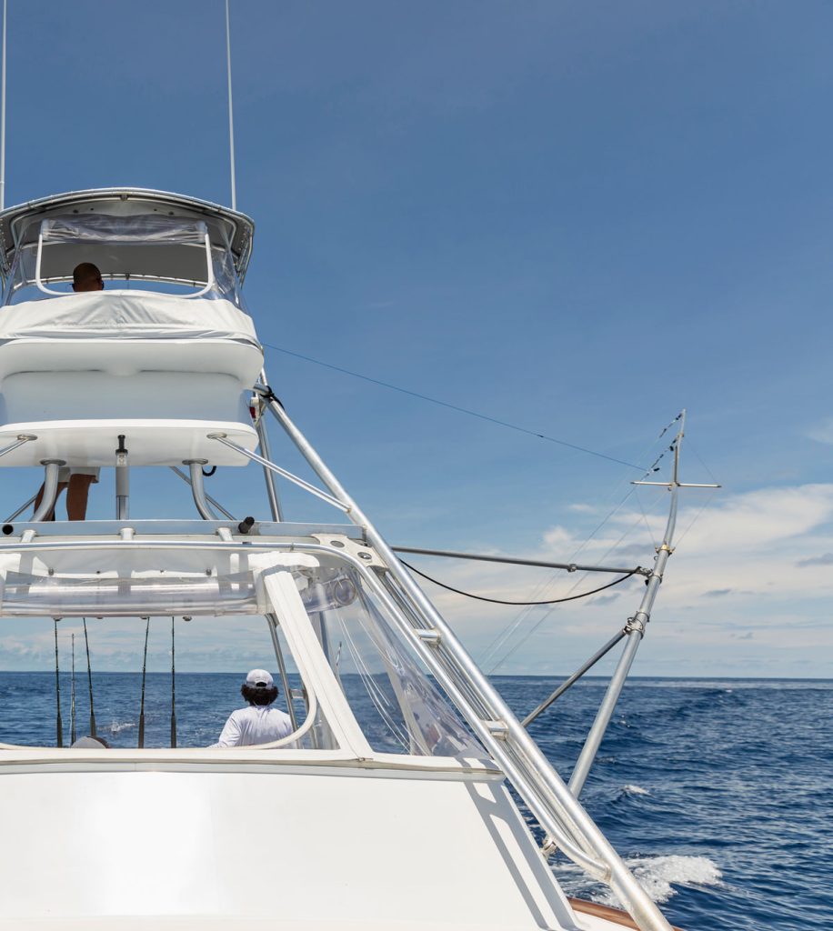 Sportfishing boat with outriggers deployed offshore, anglers at the transom